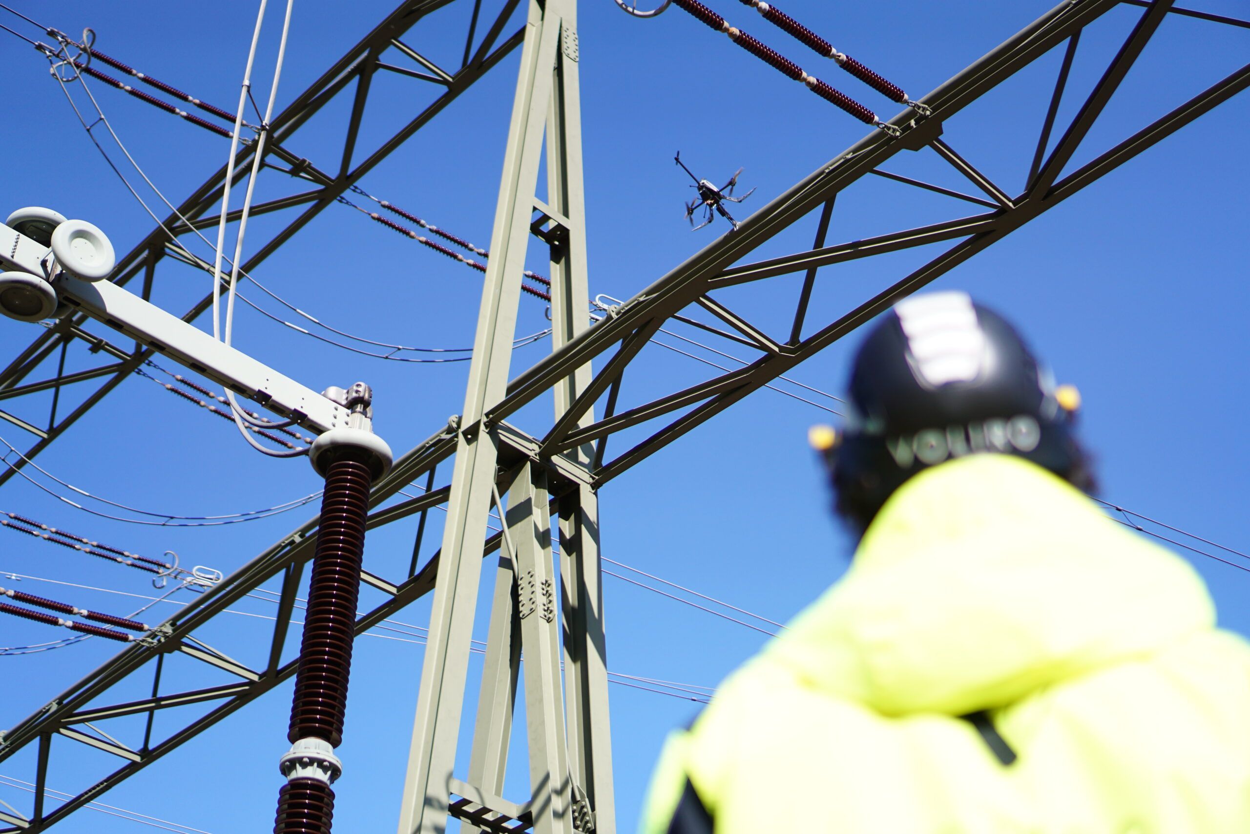 A drone pilot conducting a UT inspection using the Voliro T on a power pylon
