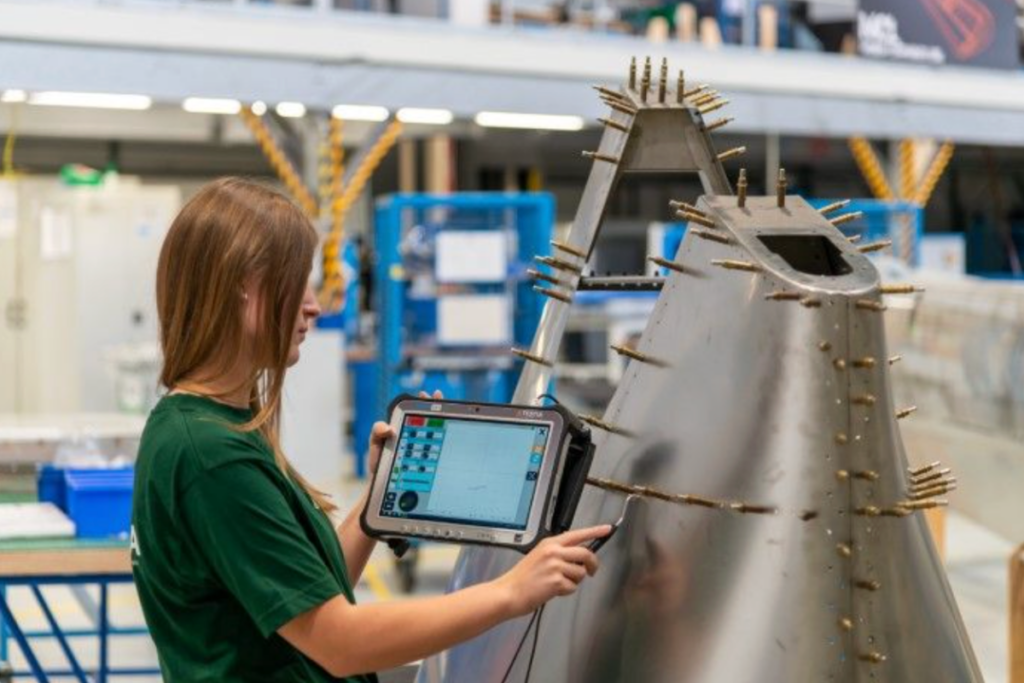 Technician inspecting an aerospace component with NDT equipment