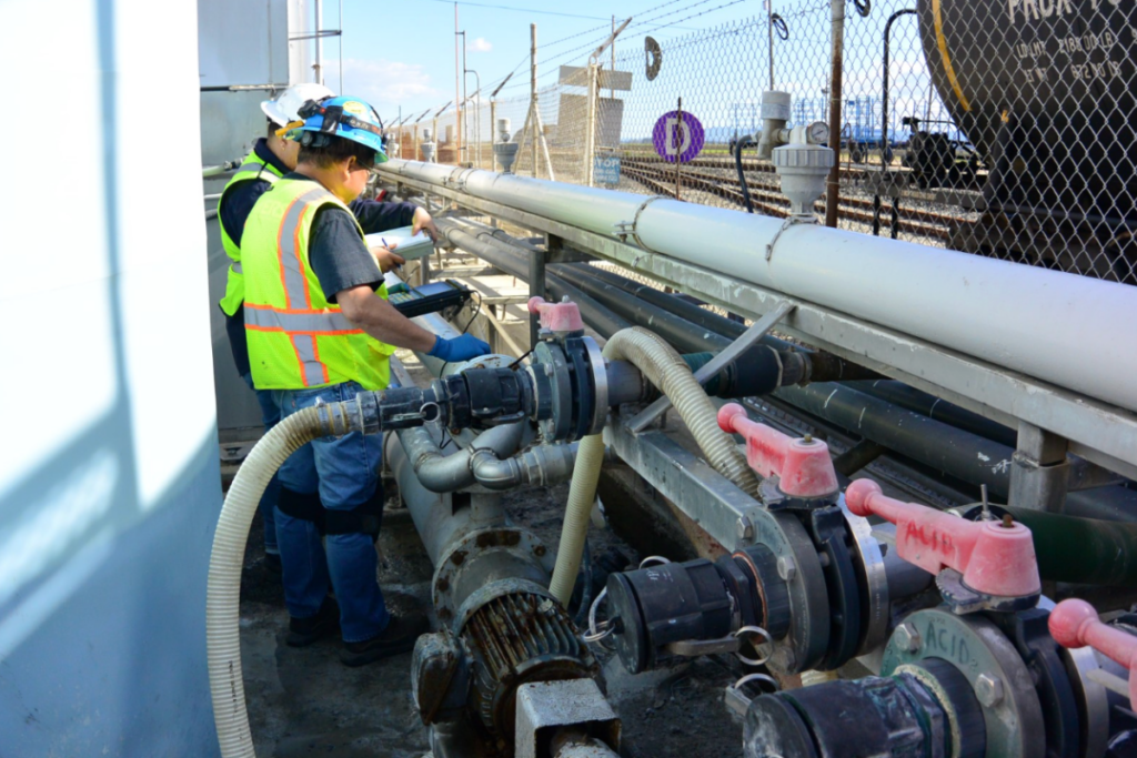 Technician inspecting piping at an industrial process facility